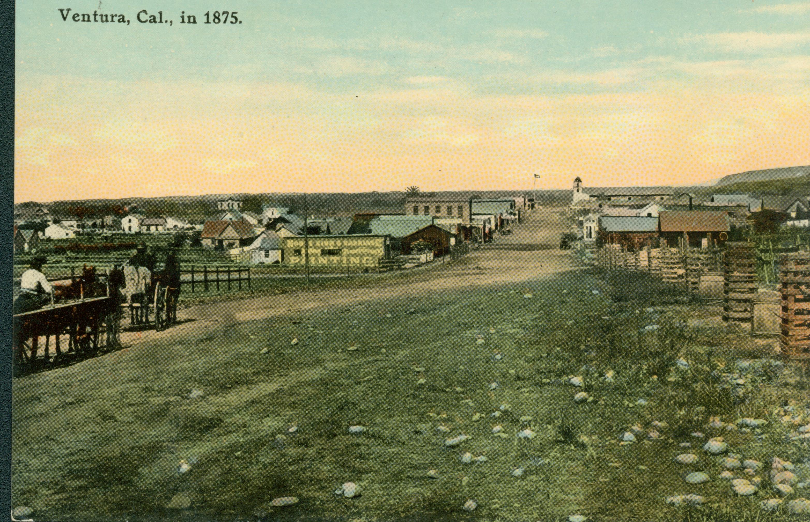 Shows a dirt road lined with buildings